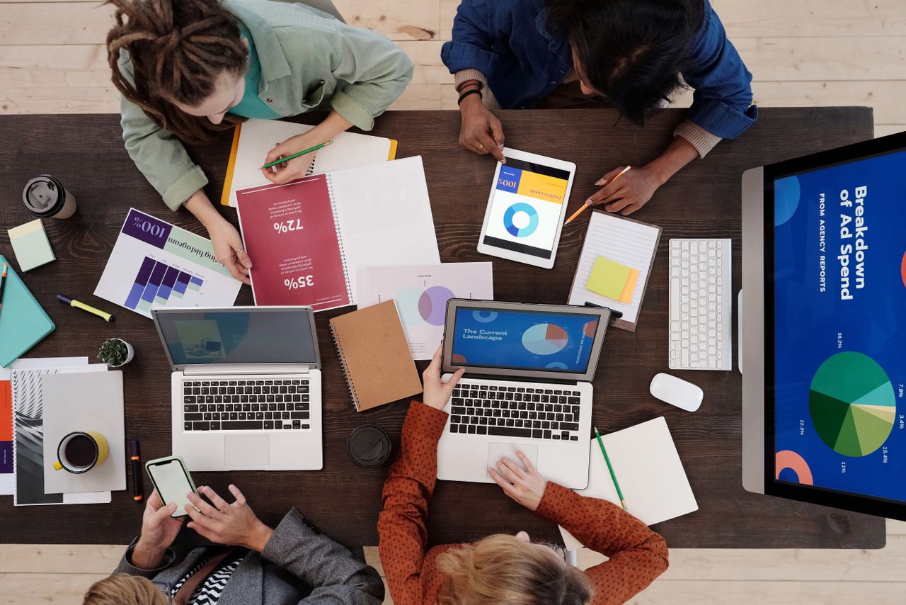 Une équipe variée travaille ensemble autour d’une table sur des stratégies de marketing digital, en utilisant des ordinateurs portables et des tablettes.